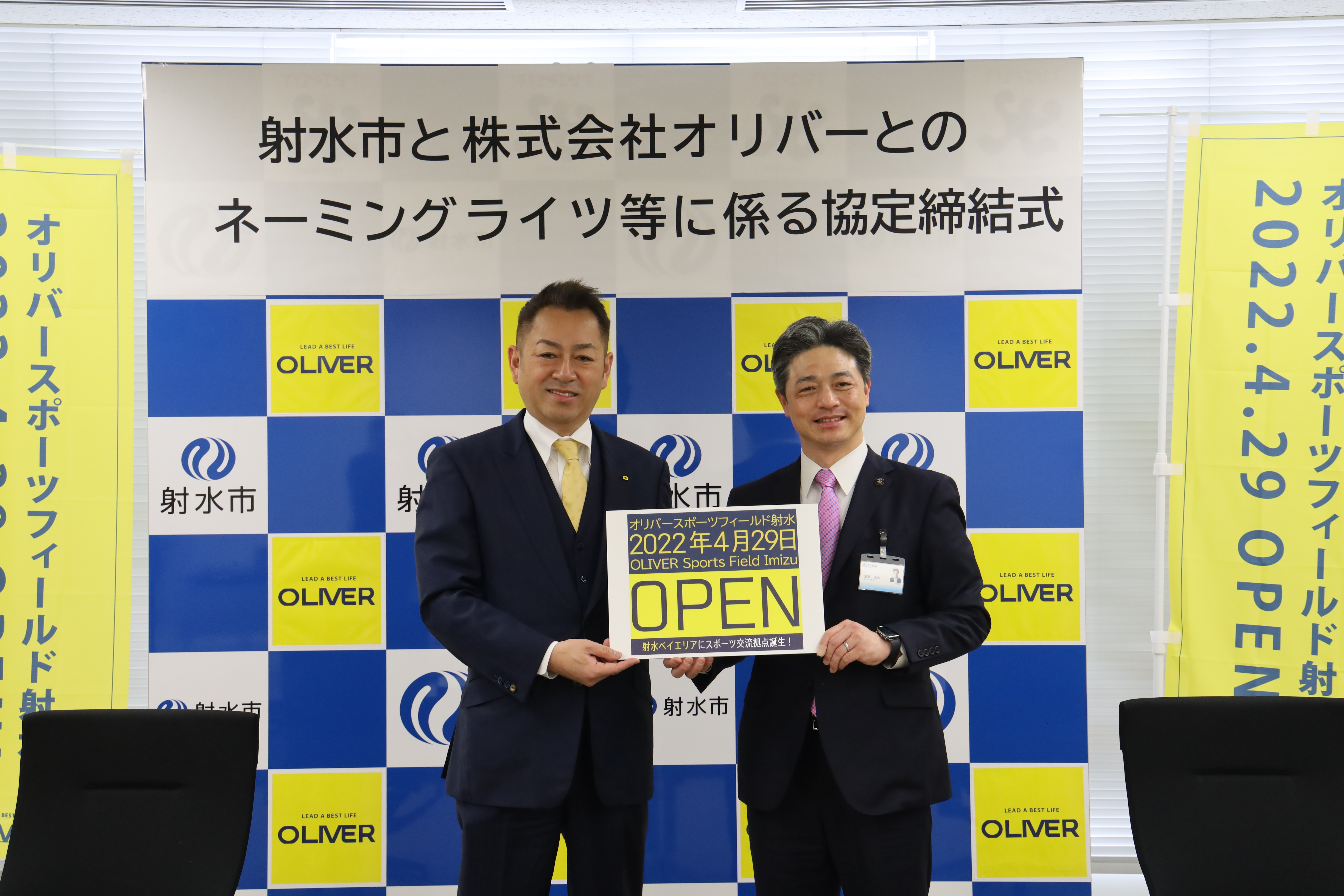 オープニング告知看板を持つ小川社長と夏野市長