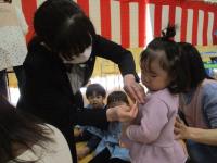 小さい組の子も園長から名札を付けてもらっている様子